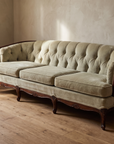 Light sage velvet tufted sofa, 45 degree three-quarter view showing full length and construction in a lived-in room