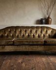 Olive velvet vintage tufted sofa, lifestyle view in a cozy room with reclaimed wood floor