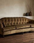 Olive velvet vintage tufted sofa, three-quarter angle showing curved front rail and tufted back