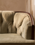 Detail of diamond button tufting and wood top rail on light sage velvet sofa