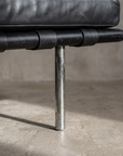 Detail of the Barcelona Daybed's round chrome leg with aged patina meeting the leather platform