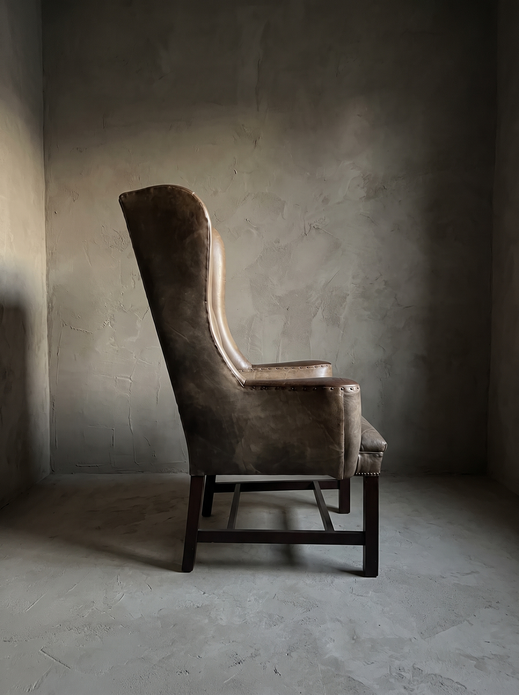 Brown leather RH wingback chair, side profile showing the wing and low arm silhouette