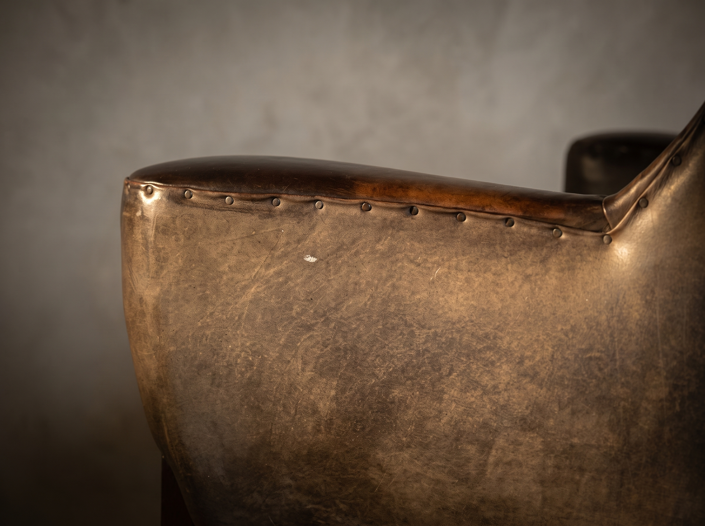 Macro detail of the nailhead trim along the arm top and the leather patina