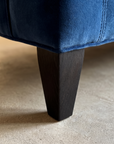 Macro detail of the tapered espresso wood leg and welted seam