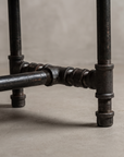 Close-up detail of the center pipe rail T-fitting junction on the iron base