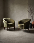 Pair of Dialogica barrel chairs in moss green chenille velvet, greige plaster room
