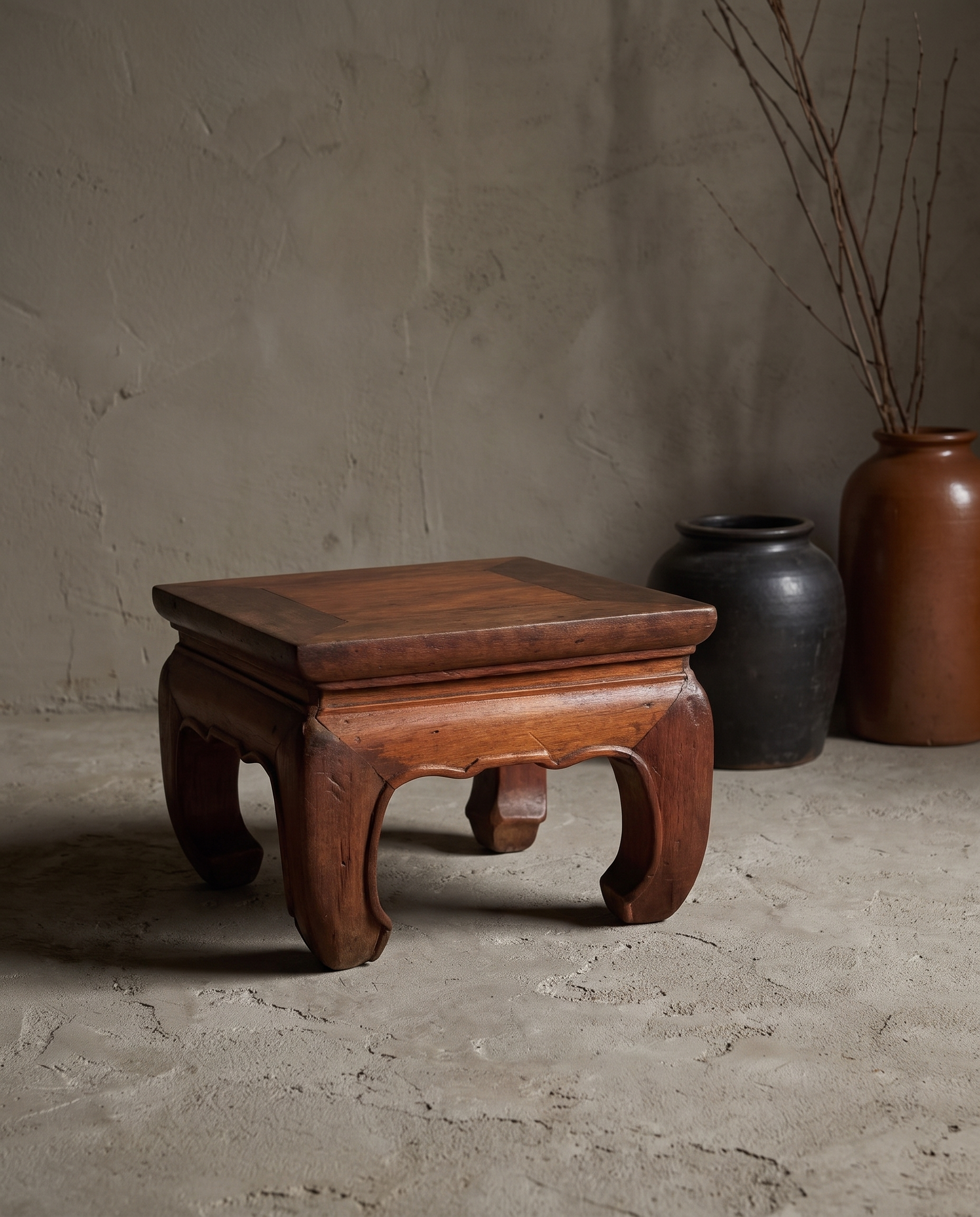 Small Kang Table, lifestyle view in a greige plaster room with stoneware vessels and dried branches
