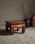 Small Kang Table, lifestyle view in a greige plaster room with stoneware vessels and dried branches
