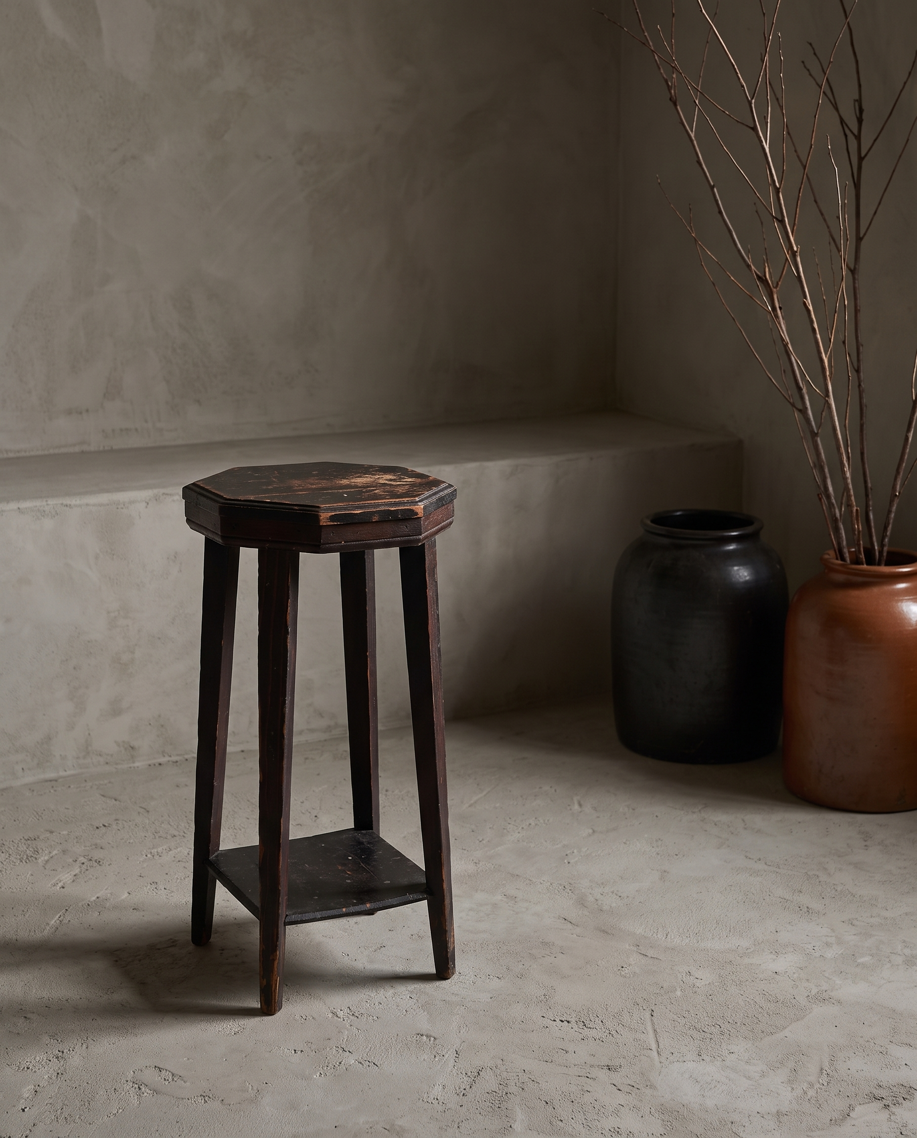 Alternate angle of the rustic accent stool in a plaster room with stoneware vessels and dried branches