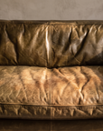 Macro detail of the cognac leather grain, creasing, and worn seat patina
