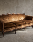 Vintage brown velvet Victorian camelback sofa, lifestyle three-quarter view in a greige plaster room