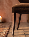 Detail of the tapered saber leg and seat cushion edge stitching, alternate angle, warm domestic room