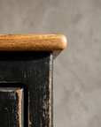 Detail of the Little Pantry Armoire's natural oak top edge meeting the black painted case