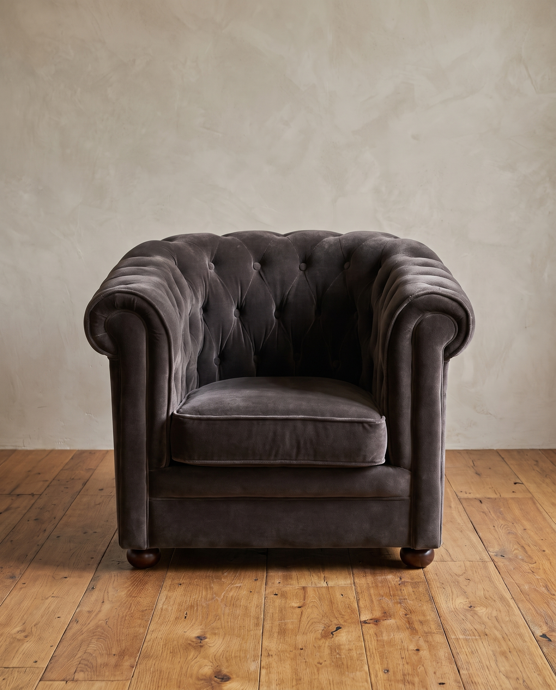 Smoke grey velvet barrel chair, front view, diamond tufted back and arms, in a plaster and reclaimed wood room