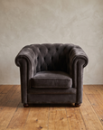 Smoke grey velvet barrel chair, front view, diamond tufted back and arms, in a plaster and reclaimed wood room