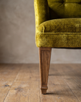 Macro detail of the square track arm and fluted tapered leg on the chartreuse velvet armchair