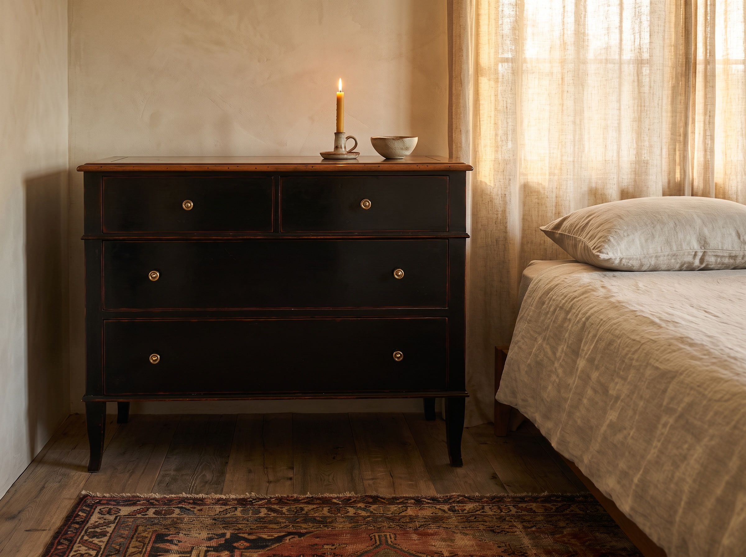 Atelier de Madeleine chest three-quarter view in a warm bedroom setting with a lit candle, kilim rug, Axel Vervoordt wabi-sabi style