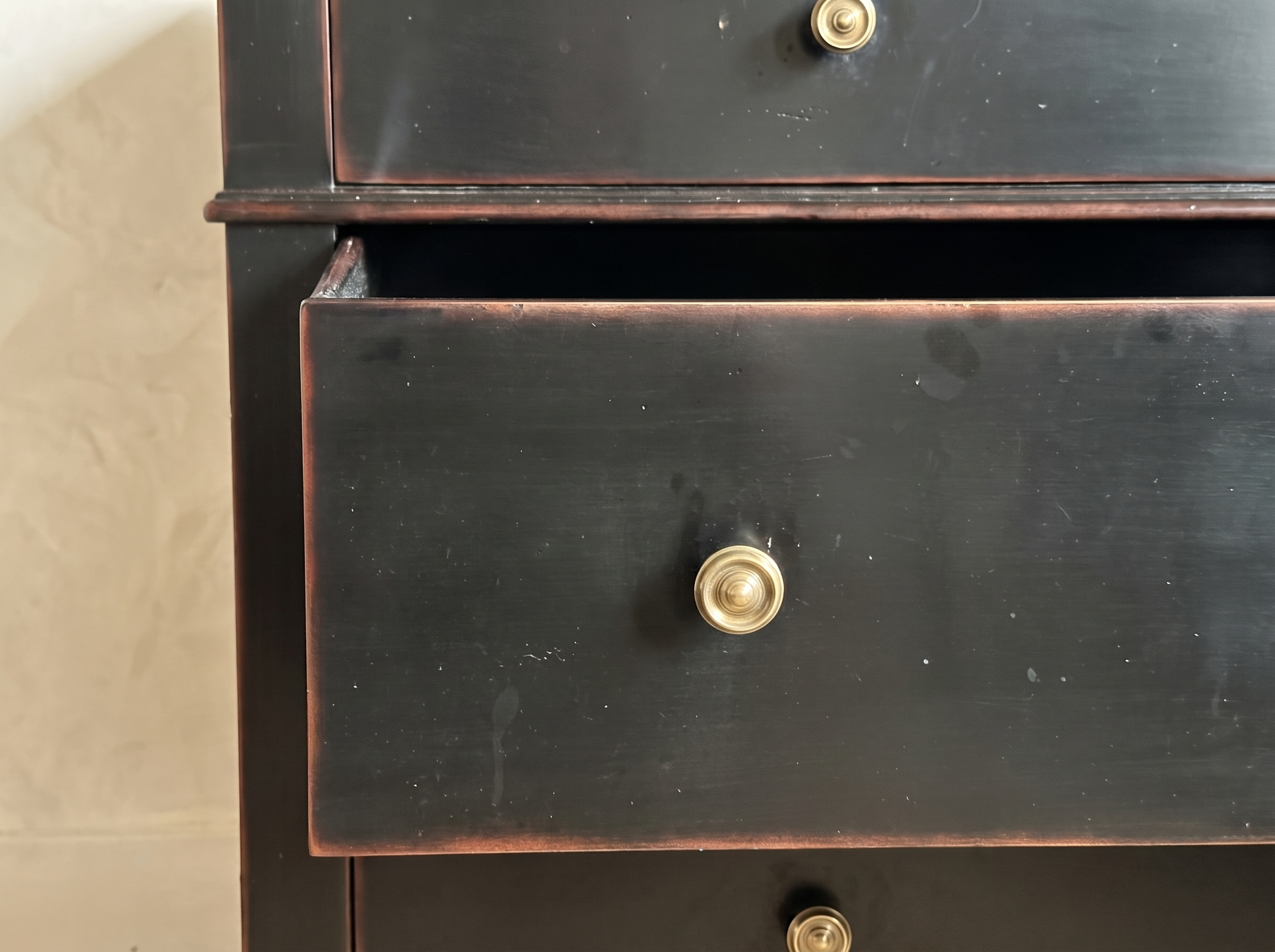 Close detail of the middle drawer pulled open, showing the drawer interior and brass knob