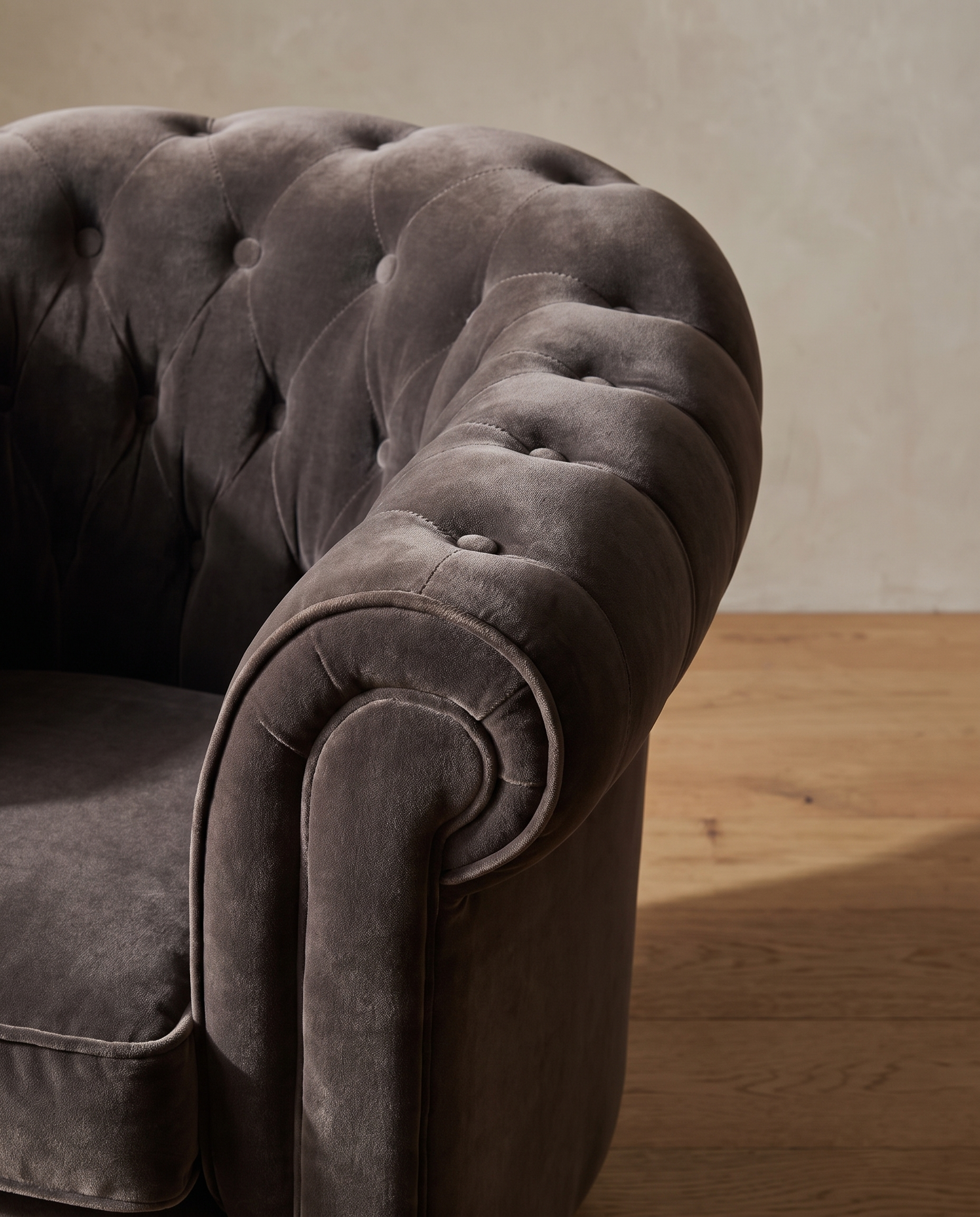 Macro detail of the diamond tufting rolling from the back into the wrapped arm on the smoke grey velvet barrel chair