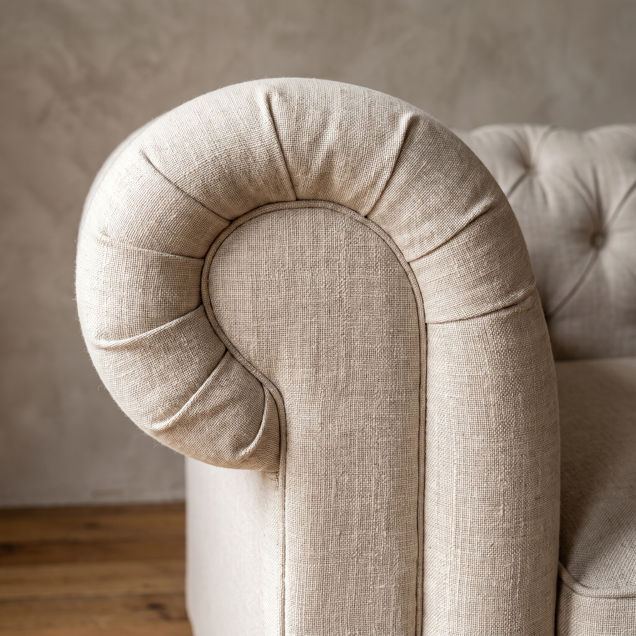 Close detail of the outward-rolled scroll arm with soft radial gathering and a welt seam