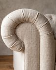 Close detail of the outward-rolled scroll arm with soft radial gathering and a welt seam