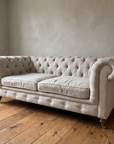Three-quarter view of the oat linen Chesterfield showing the rolled arms and relaxed seat cushions