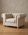 The chesterfield chair seen at forty-five degrees, showing its low deep proportions and turned wood feet