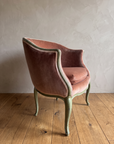 Side profile of the rose velvet bergère showing the curved gondola back and pink gimp trim