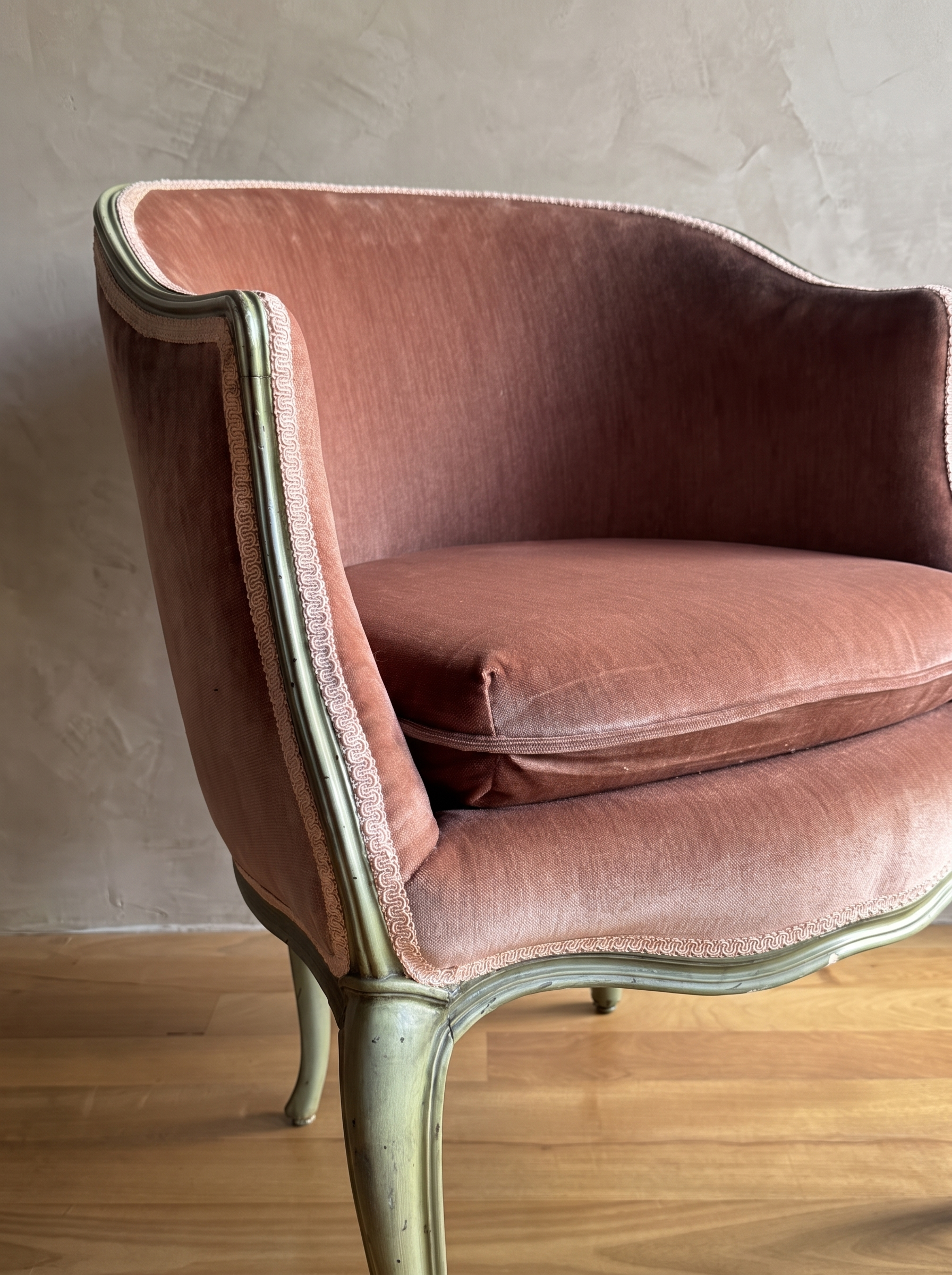 Close-up of dusty rose velvet, pale pink gimp braid, and worn sage green painted frame