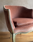 Close-up of dusty rose velvet, pale pink gimp braid, and worn sage green painted frame