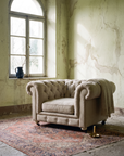 The chair in a room of weathered plaster beneath an arched window, a wool throw over one corner and a faded antique rug underfoot