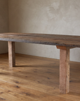 Long side view of the redwood dining table showing the plank top, staggered plank ends and four square redwood legs