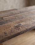 Close-up of the weathered redwood plank top with a knot, raised grain and open seams