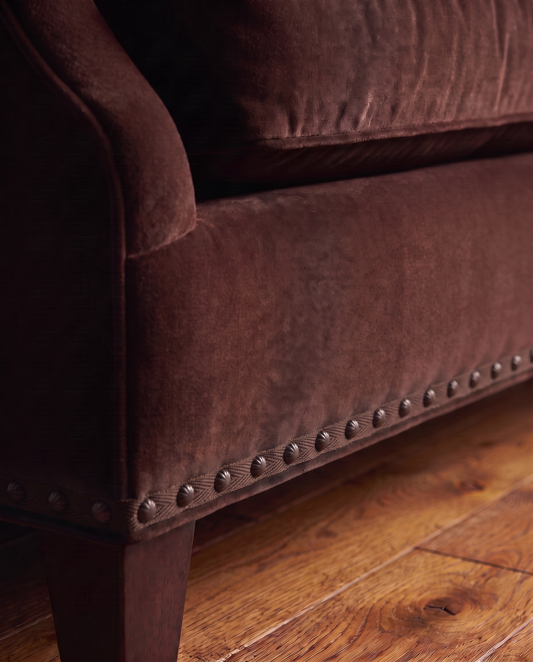 Detail of the tapered leg, self-tone herringbone braid, and fluted bronze nailhead trim on the Taylor King sofa