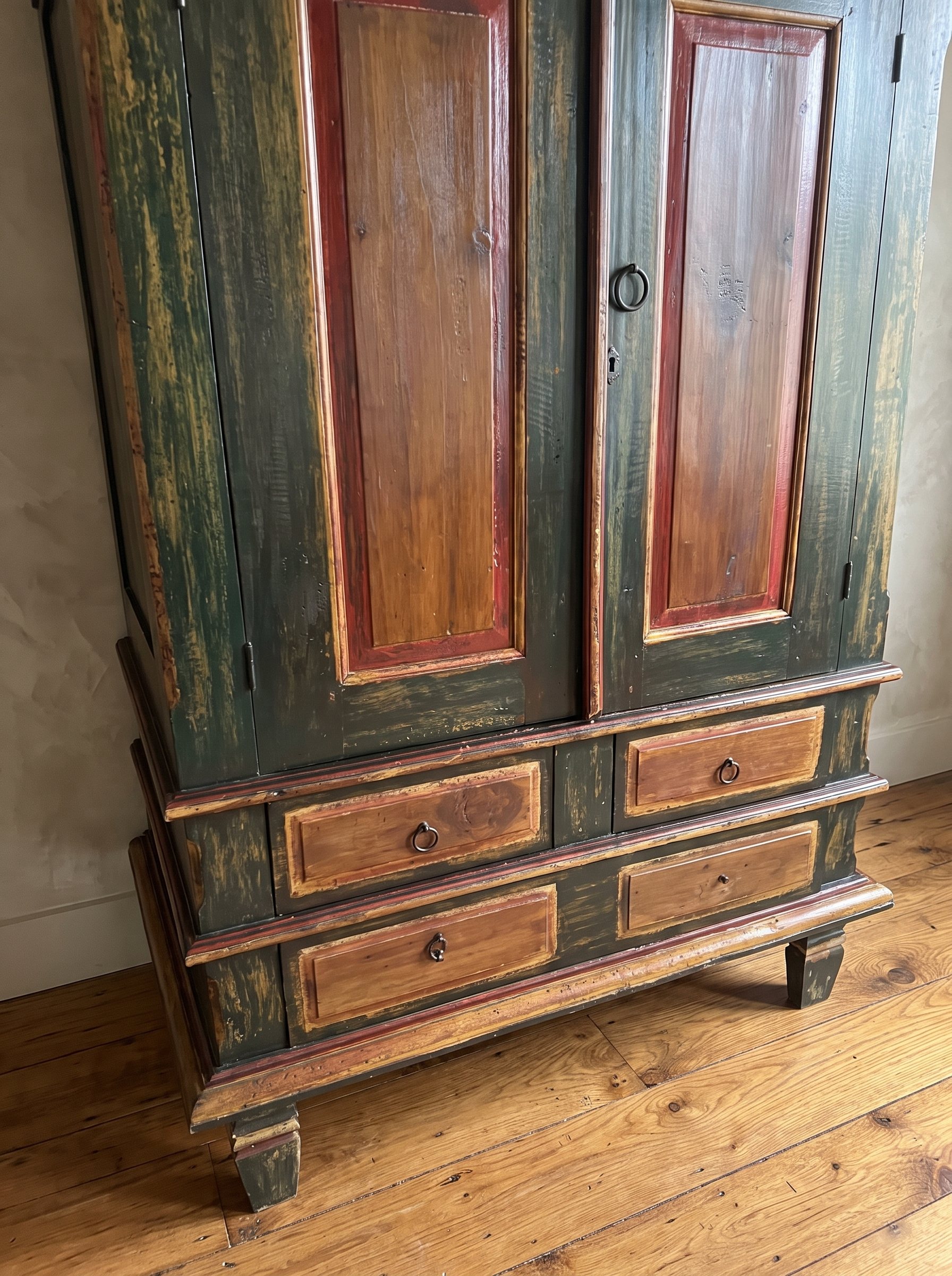 Close detail of the armoire's four-drawer base with red-brown drawer panels, iron ring pulls, and block feet