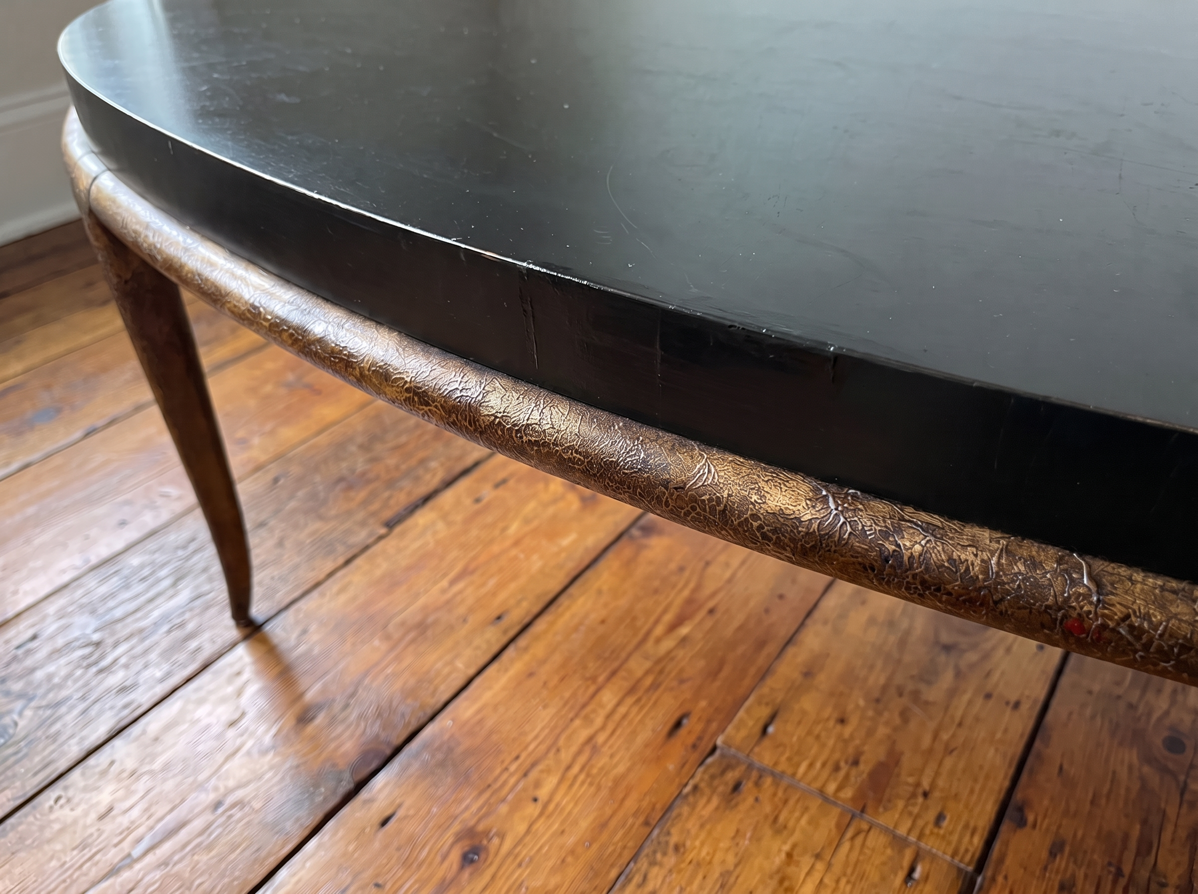 Close-up of the crackled bronze rim and black edge band of the oval coffee table