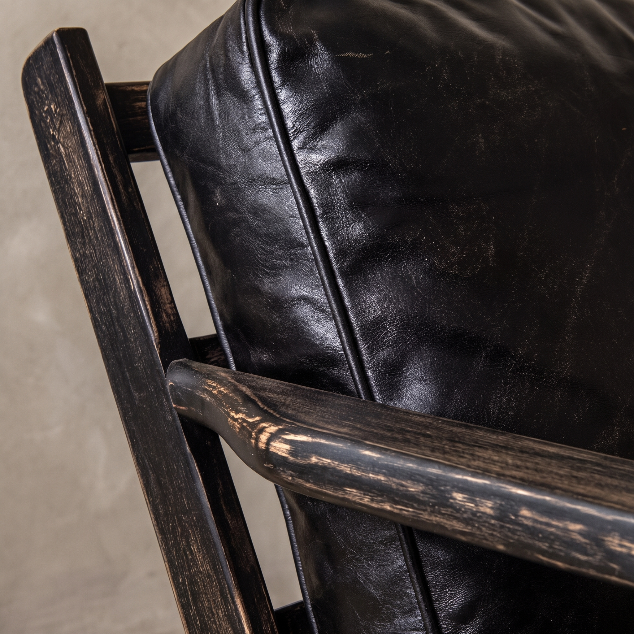 Close-up of the distressed black oak paddle arm against the black leather back cushion