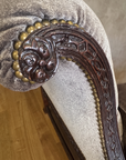 Close-up of the hand-carved leafy arm end ringed in large brass nailheads, with lattice fretwork facing