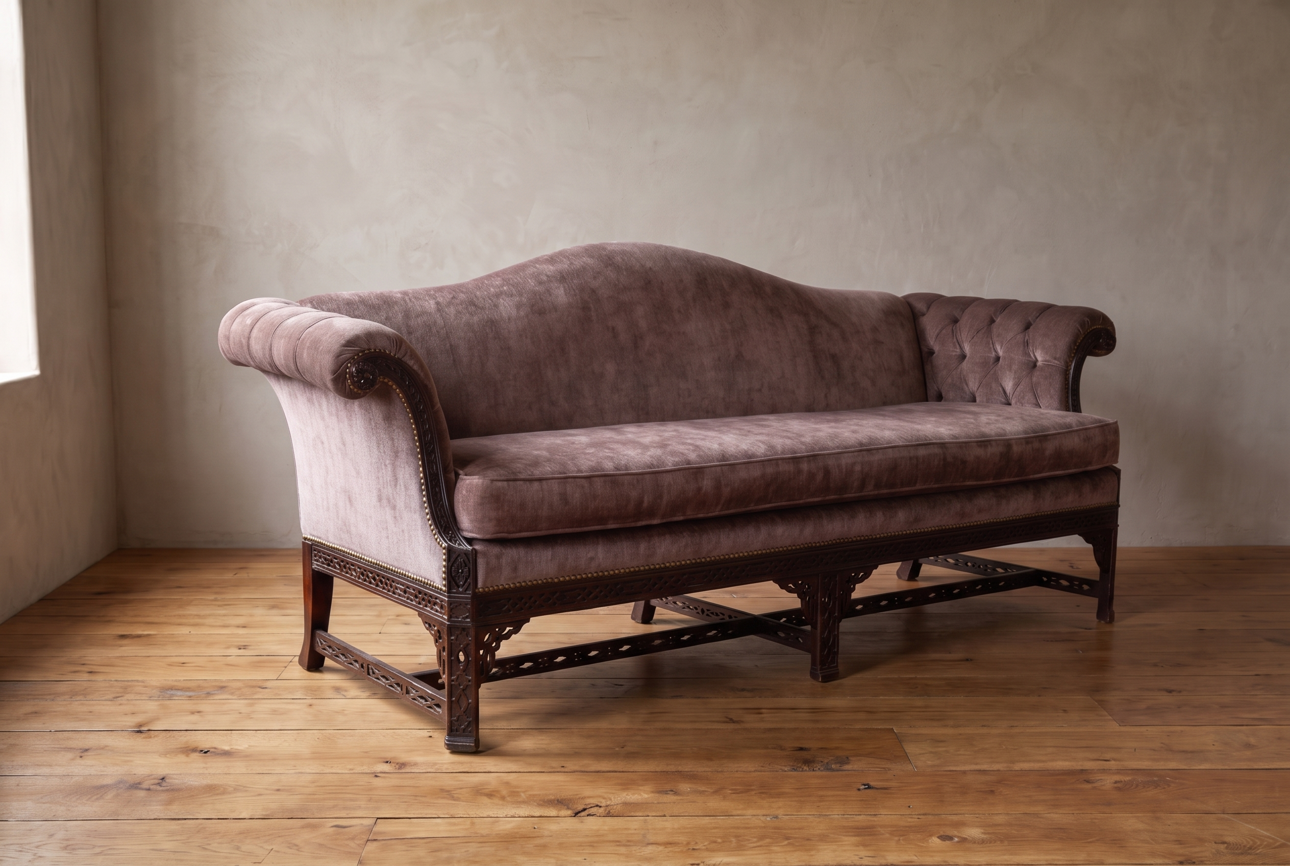 Mauve velvet Chinese Chippendale camelback sofa, front view, against a plaster wall on a reclaimed wood floor