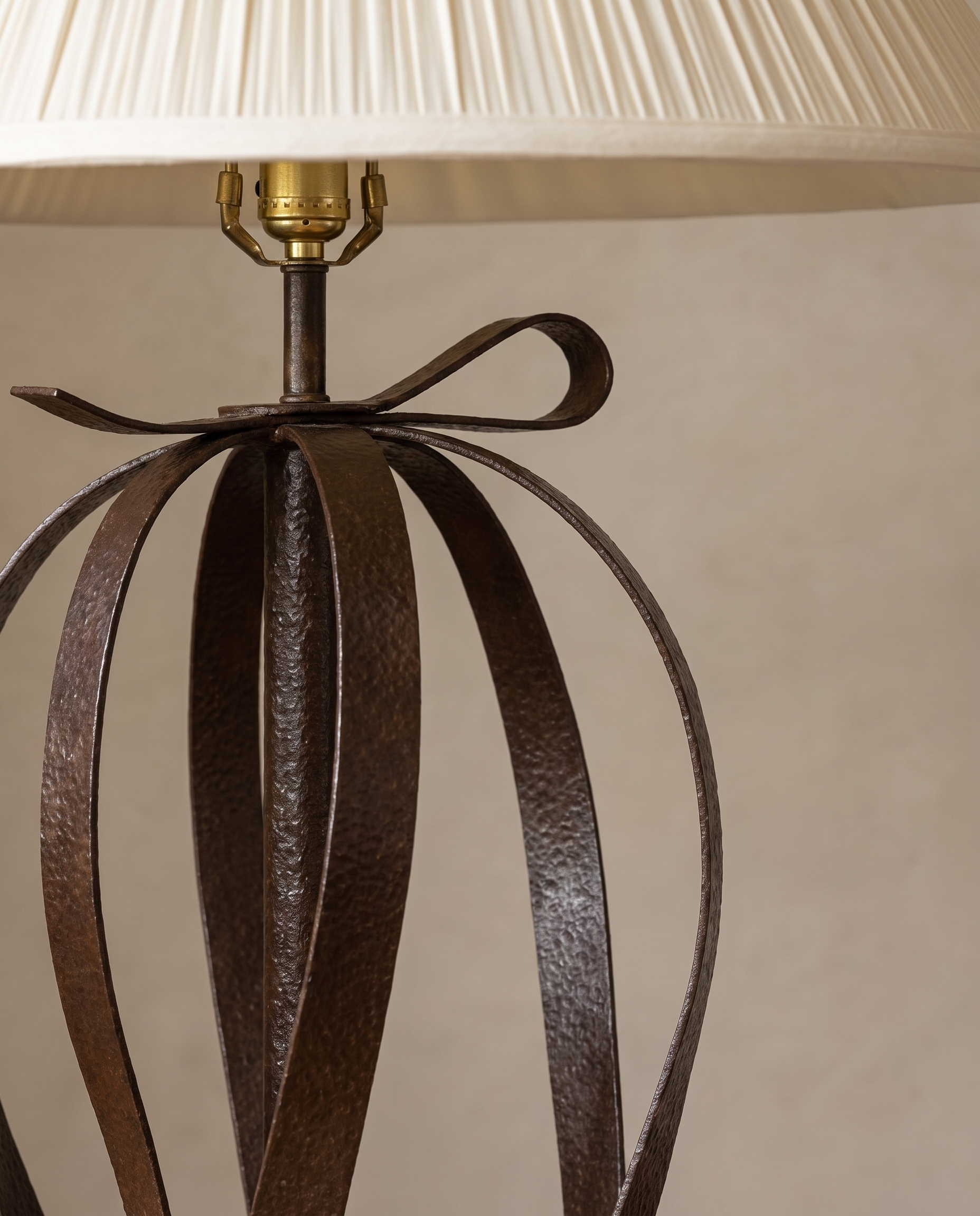 Steel bow at the top of the lamp beneath the pleated shade