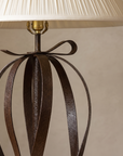 Steel bow at the top of the lamp beneath the pleated shade