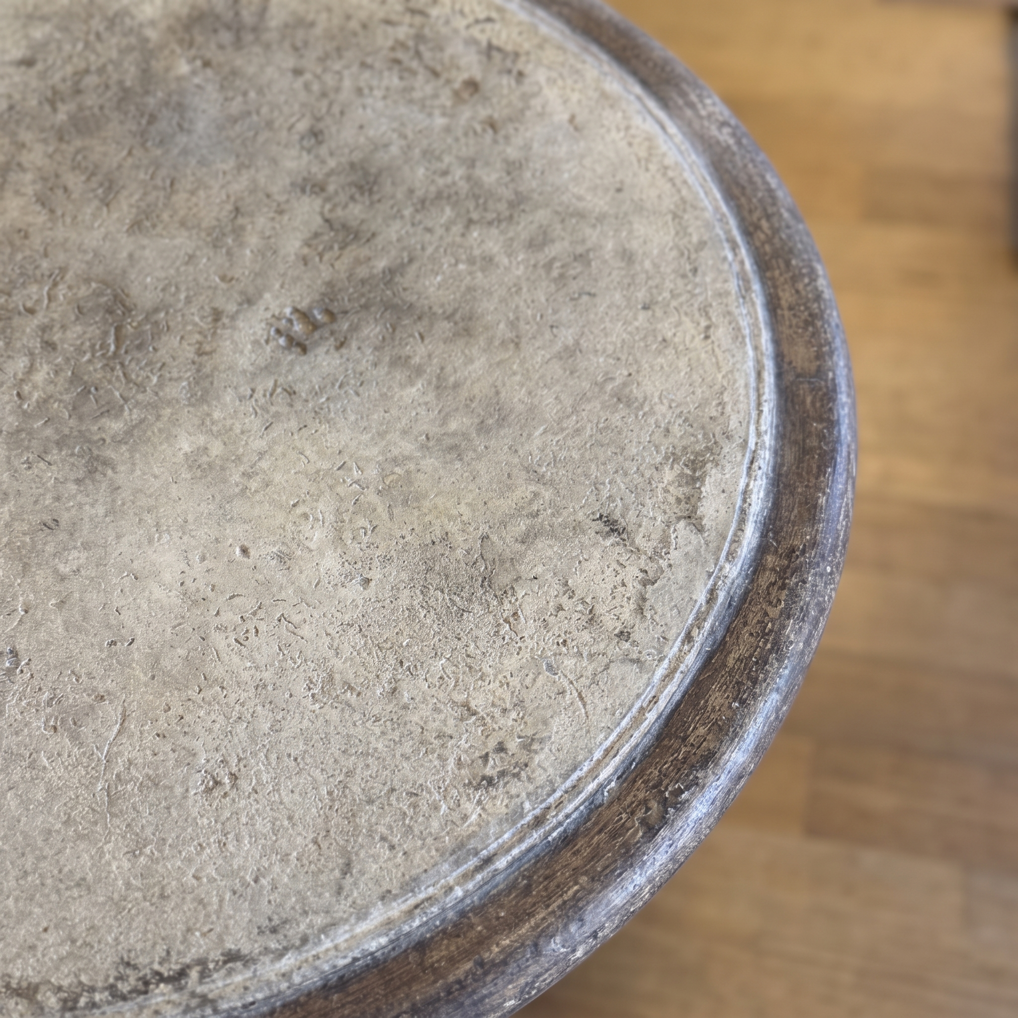 Close-up of the weathered cement tabletop set in a dark iron rim