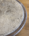 Close-up of the weathered cement tabletop set in a dark iron rim