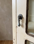 Close-up of the pewter drop pull on the cream painted cabinet door