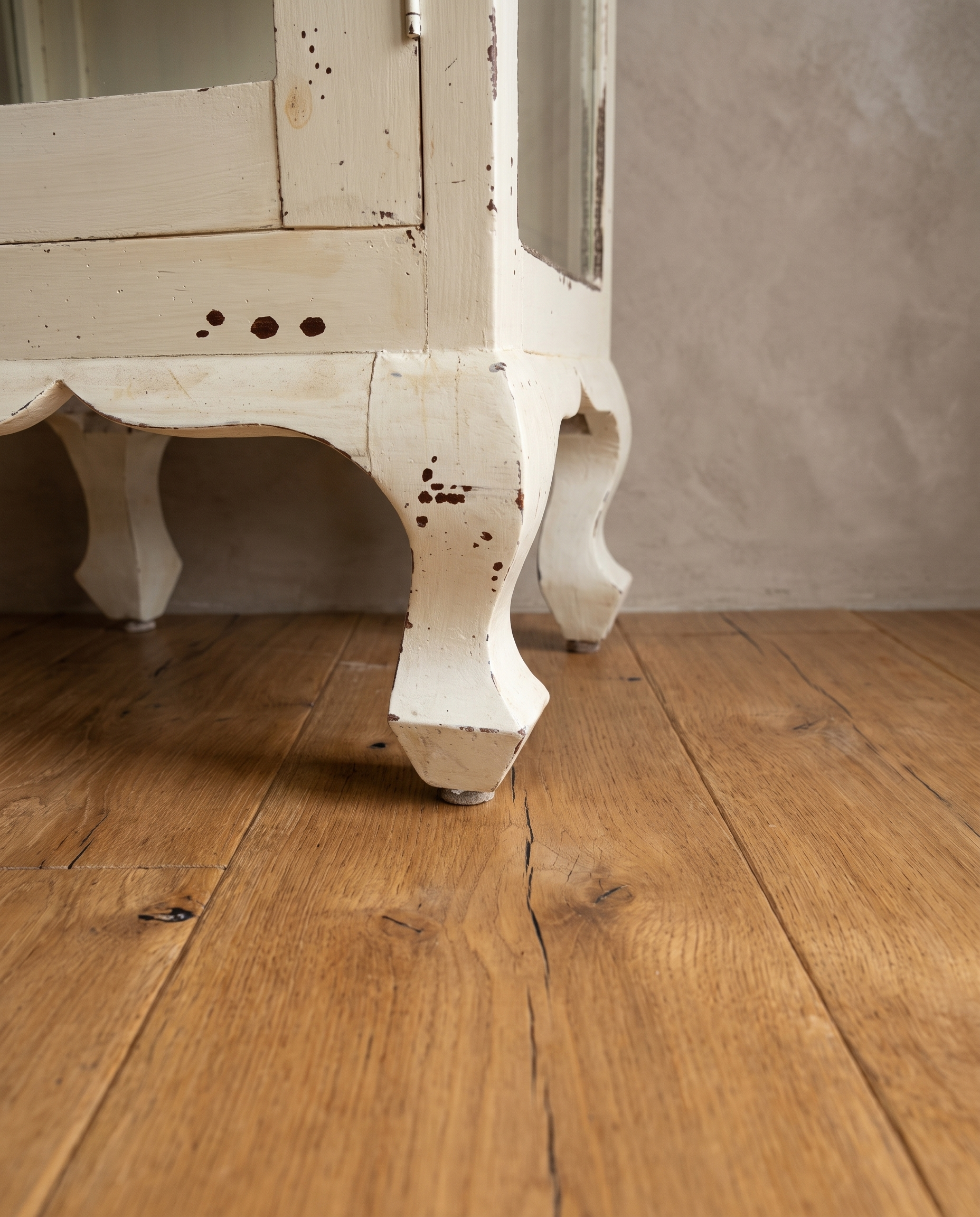 Carved cabriole legs and scalloped apron of the cabinet on a reclaimed wood floor