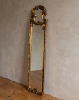 Three-quarter view of the carved gilt scroll mirror frame