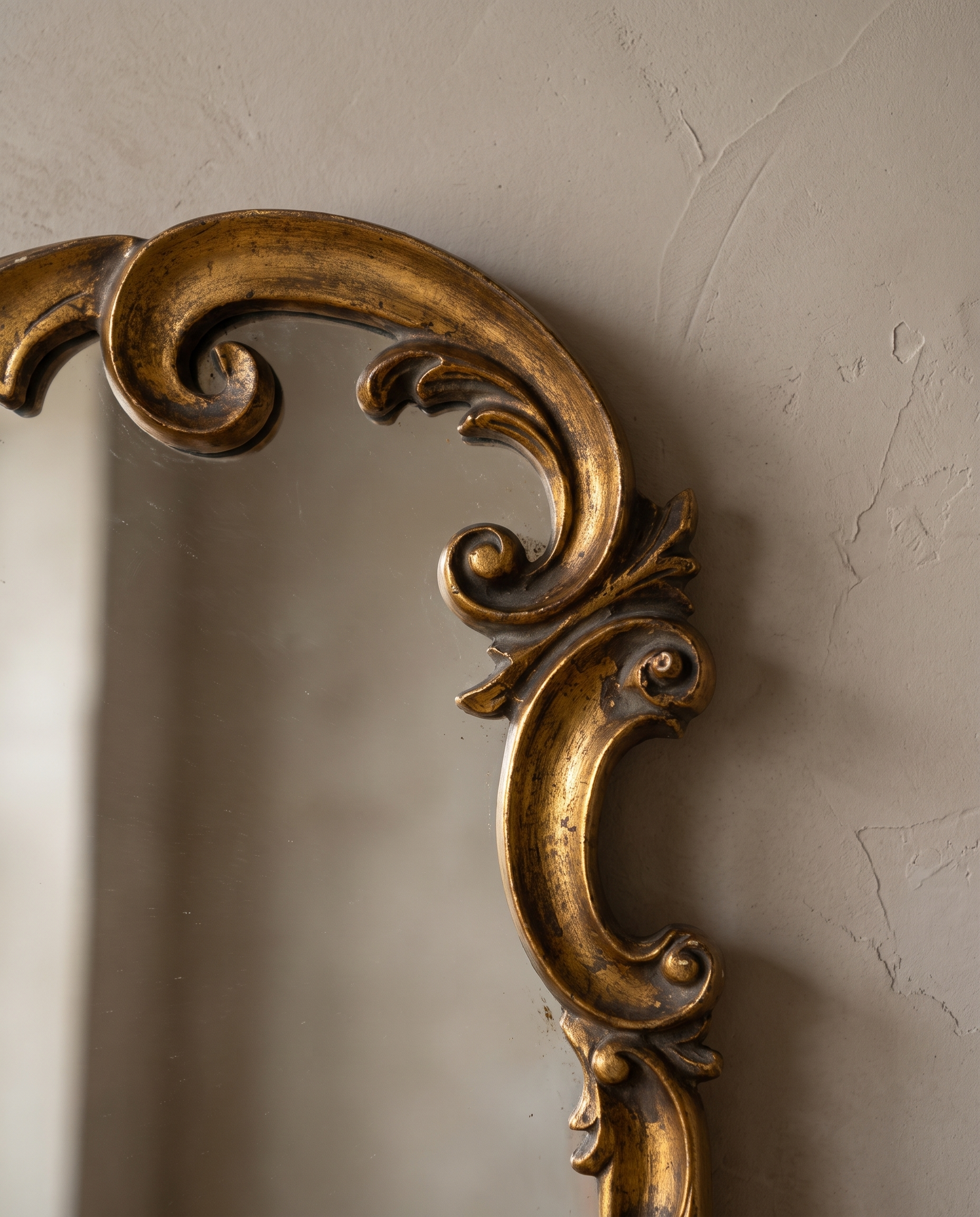 Close-up of the carved rococo scrollwork and worn gilt on the mirror crown