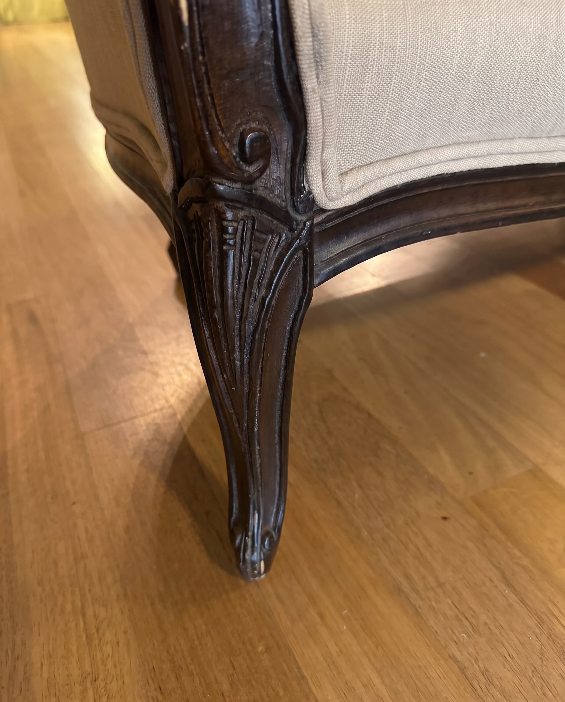 Close-up of the carved cabriole leg and front corner of the settee frame
