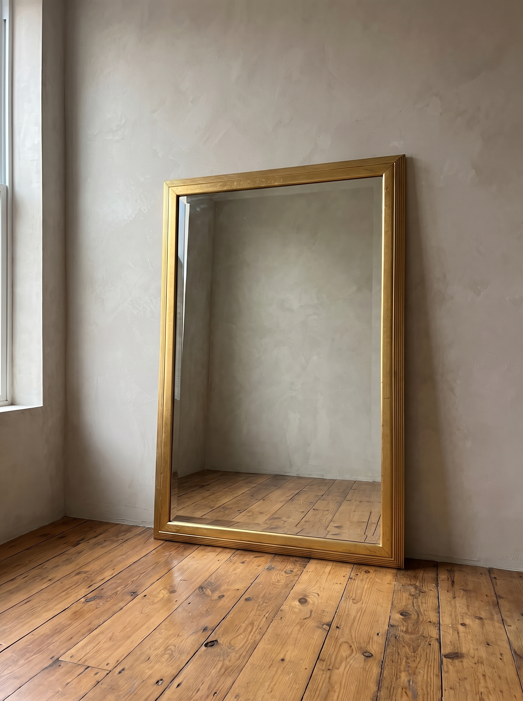 Gilt reeded mirror leaning near a window in natural daylight