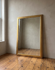 Gilt reeded mirror leaning near a window in natural daylight